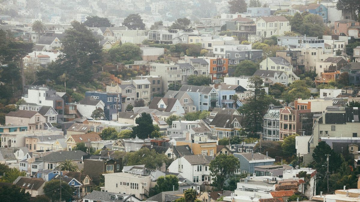 Scenic view of the foggy San Francisco hills with colorful houses under a cloudy sky.