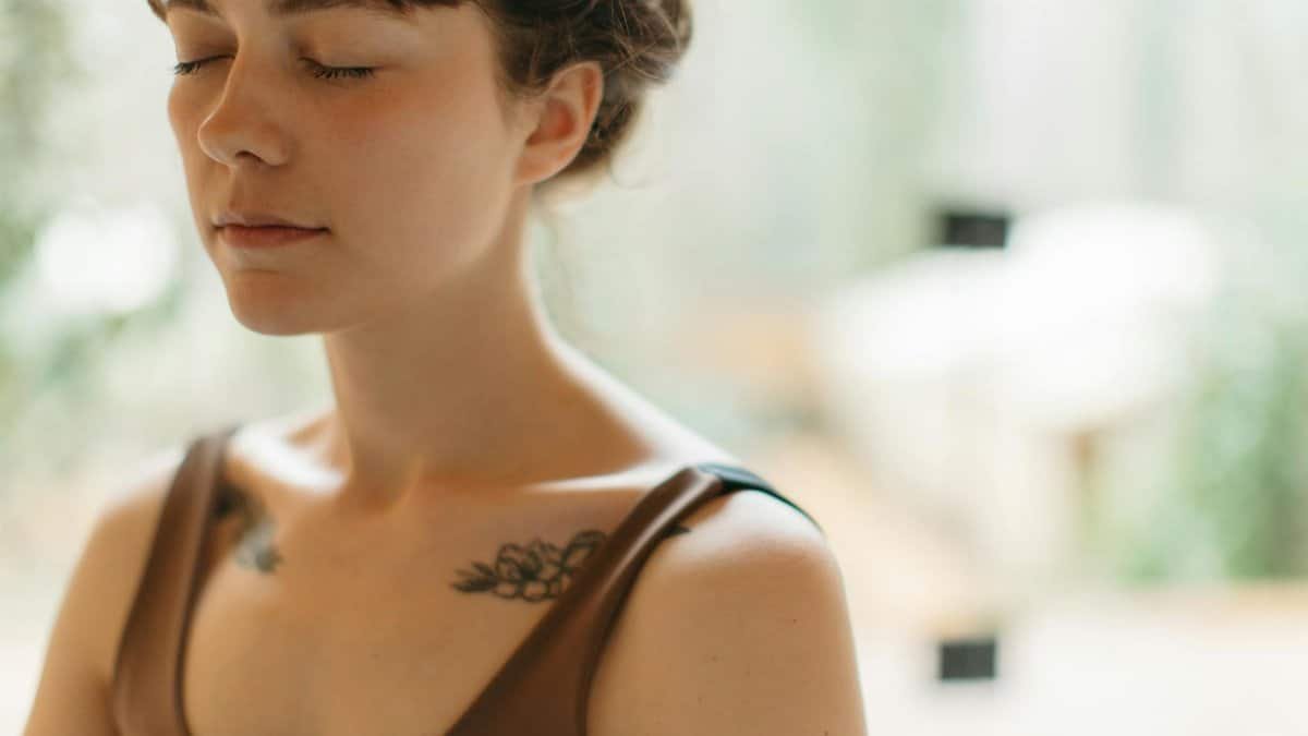 Woman with closed eyes meditating indoors, symbolizing tranquility and focus.