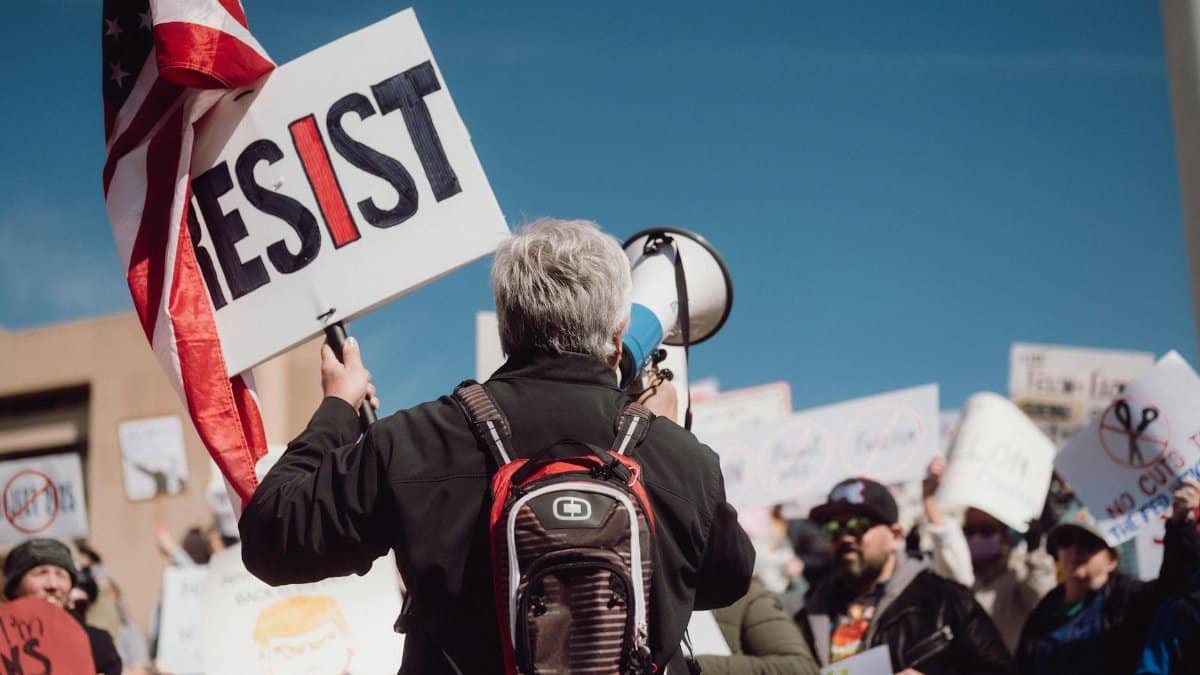 Crowd at a rally holding signs with a strong message of resistance.