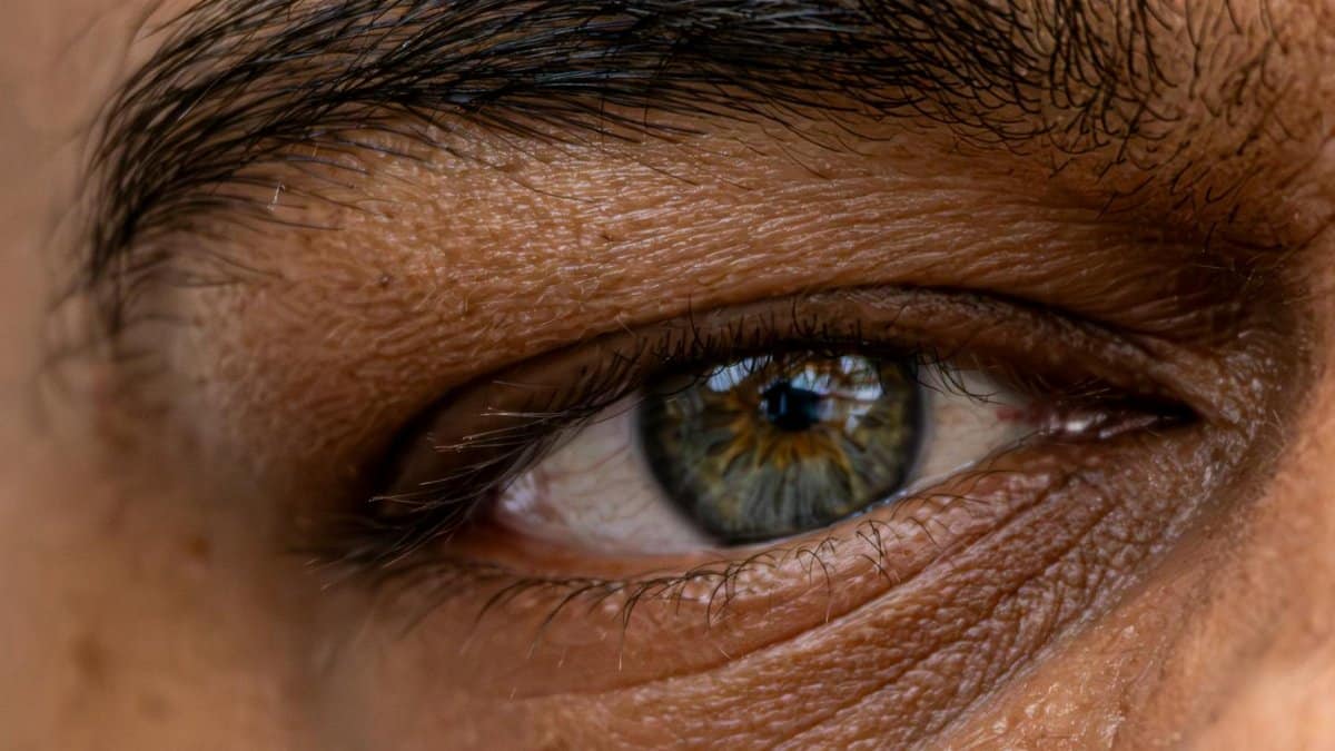 Detailed close-up photo of a blue-green eye with fine skin texture and eyebrow detail.