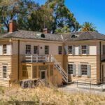 Old mansion at Angel Island State Park with ocean view and natural landscape under clear blue sky.