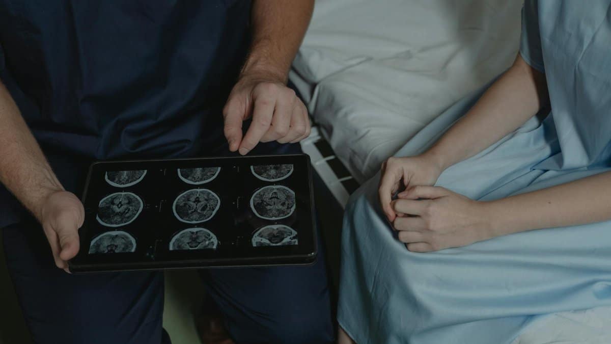 A doctor shows and explains brain scan images to a patient in a medical setting.
