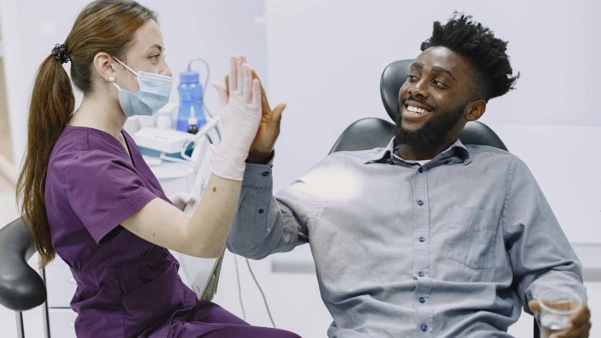 Patient high-fiving a dental professional after a successful checkup in a modern clinic.