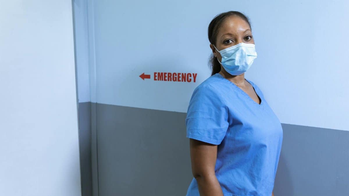 Nurse wearing mask in hospital emergency corridor for safety.