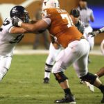 Athletes in action during an American football game on a grassy field.