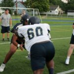 Dynamic scene of American football players in action during practice. Focus on teamwork and strategy.