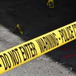 Yellow police crime scene tape marking a restricted urban area on concrete ground.