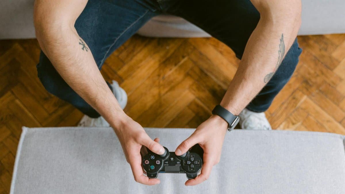A man sitting on a couch holds a game controller, ready to play video games.