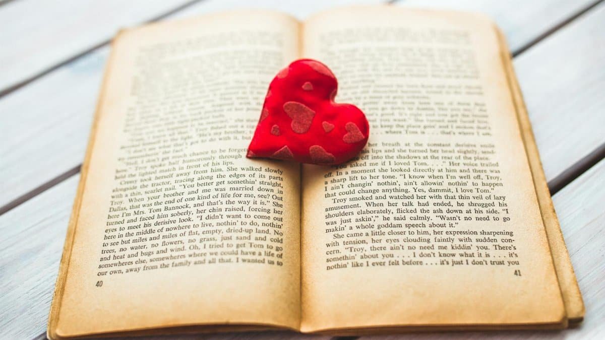 A red heart rests in an open vintage book, evoking romance.