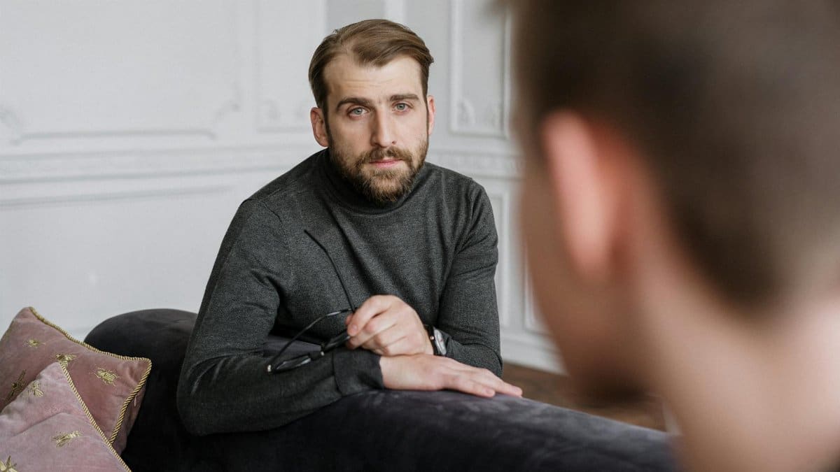 A therapist engages in a focused psychotherapy session with a patient in an indoor setting.