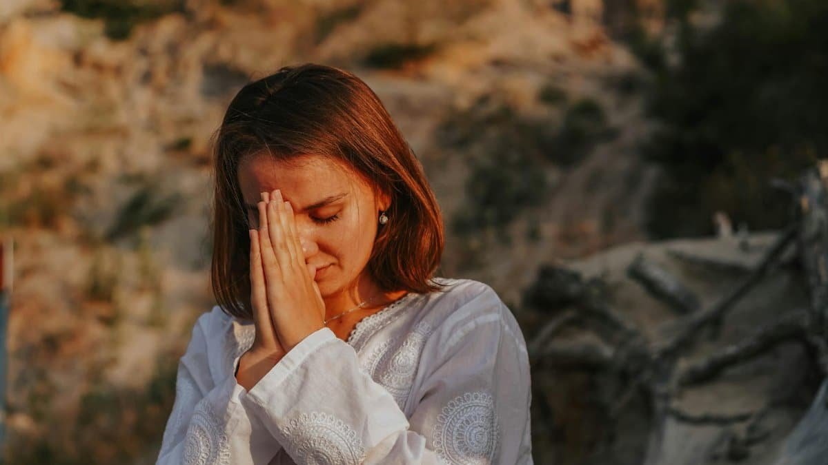 A woman meditates outdoors, eyes closed, demonstrating a peaceful pose and mental clarity.