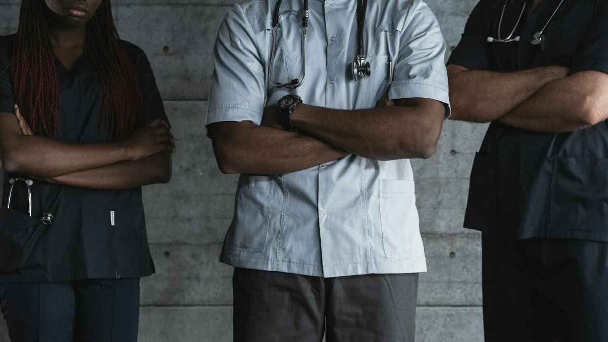 Group of medical professionals standing confidently with folded arms in uniform.