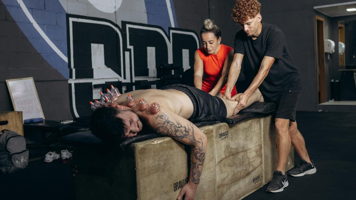 Athlete receives cupping therapy and massage for recovery in a gym setting.