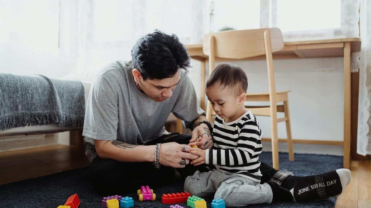 Father and son bond playing with colorful blocks in a cozy home setting.