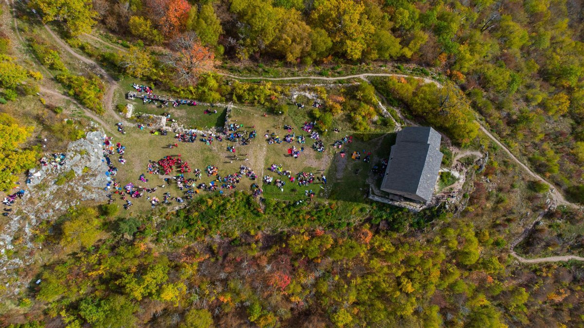Aerial shot of a crowd gathered near historical ruins in a forested area of Kakanj, Bosnia.