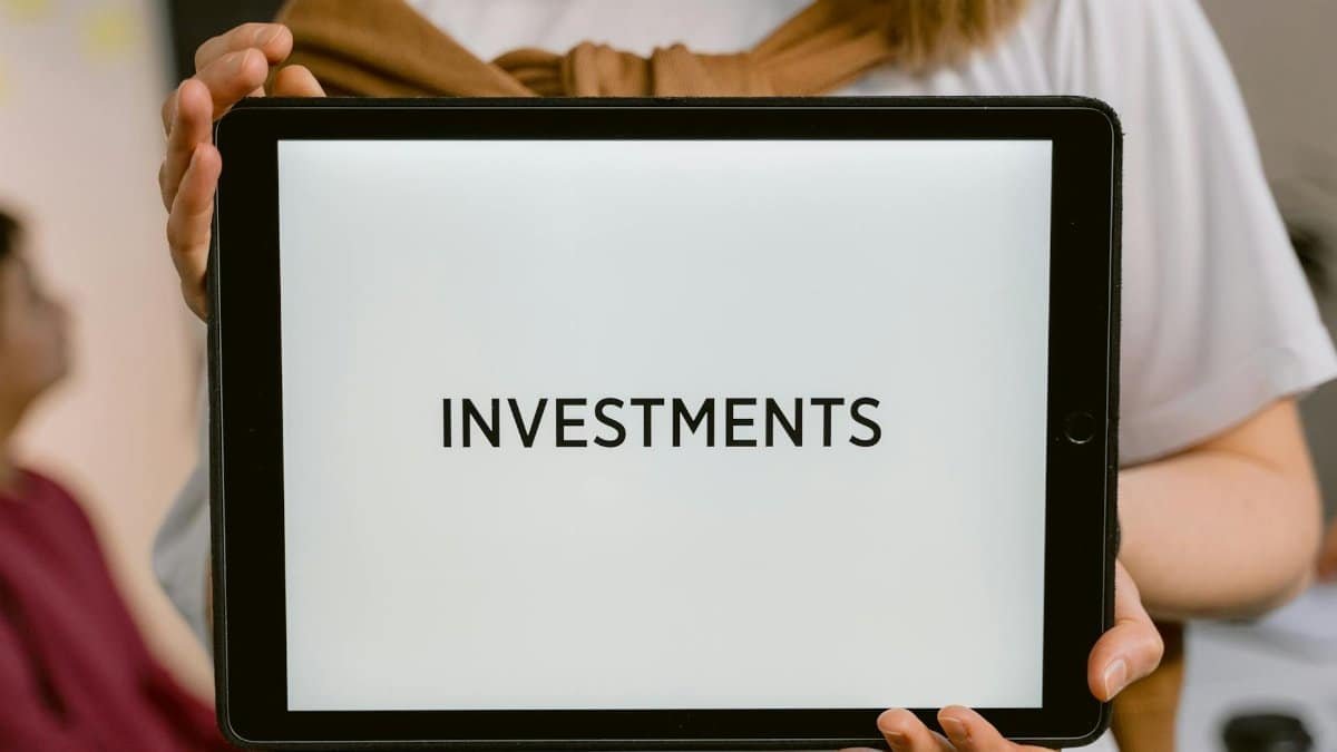 Close-up of a tablet with the word 'Investments', held by a person. Ideal for financial topics.