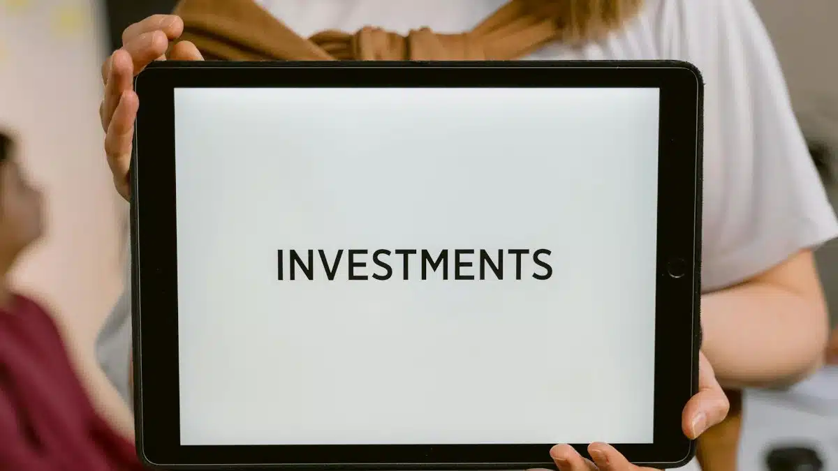 Close-up of a tablet with the word 'Investments', held by a person. Ideal for financial topics.
