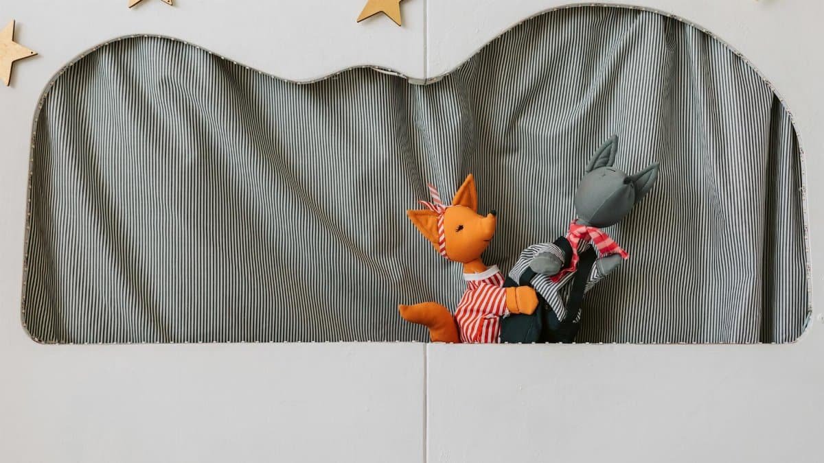 Bright puppet theater setup with two animal puppets performing on stage.