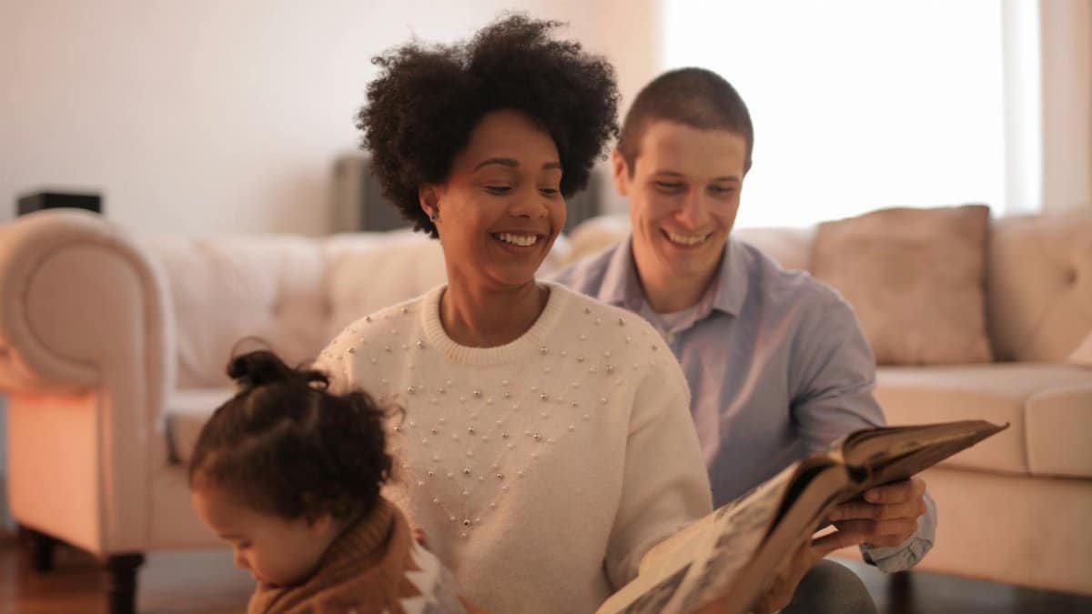 A family shares joyful moments reading a storybook indoors, creating cherished memories.