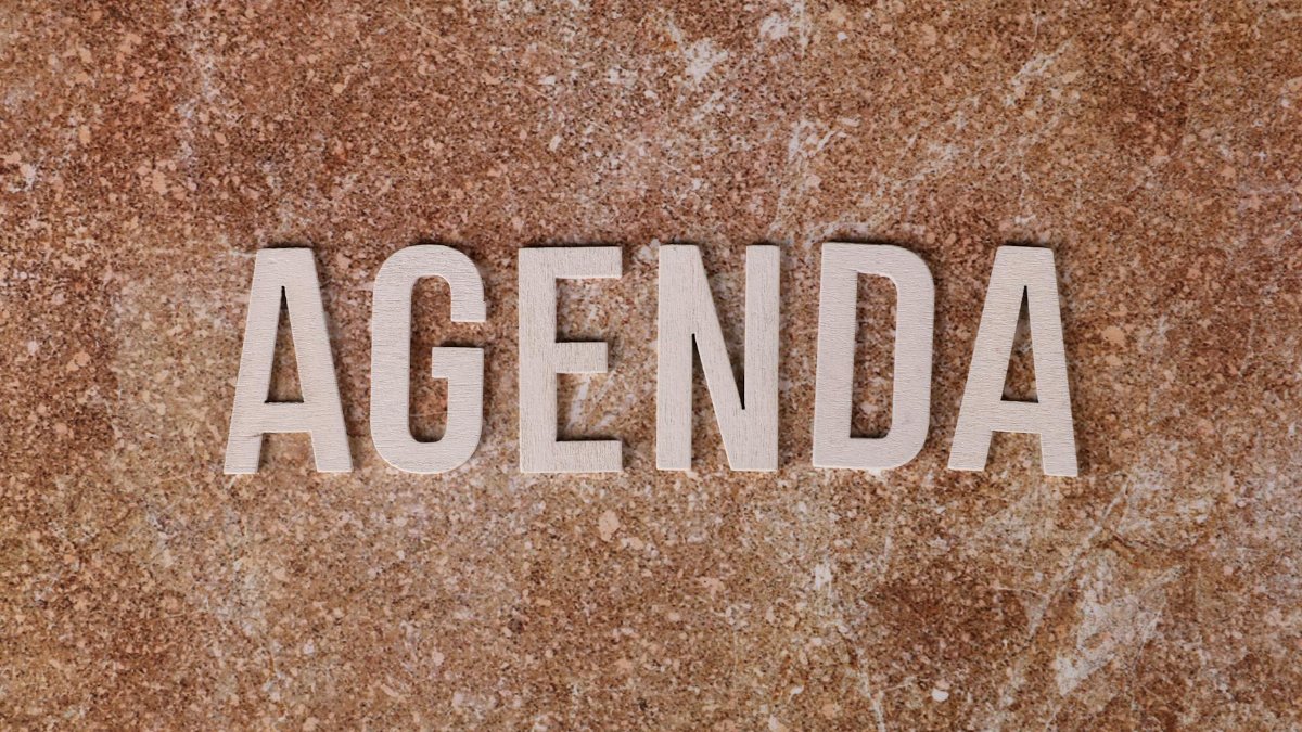 The word 'Agenda' spelled out with wooden letters on a textured brown surface.