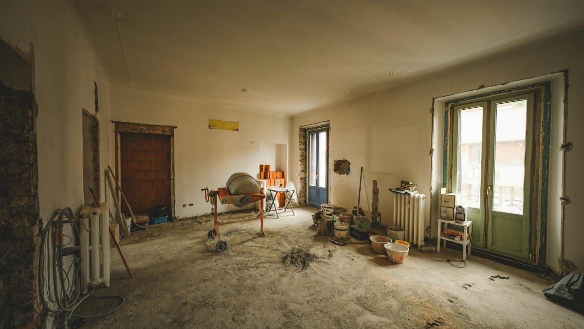 Wide view of a sunny room under renovation with construction materials and tools present, ideal for home improvement concepts.