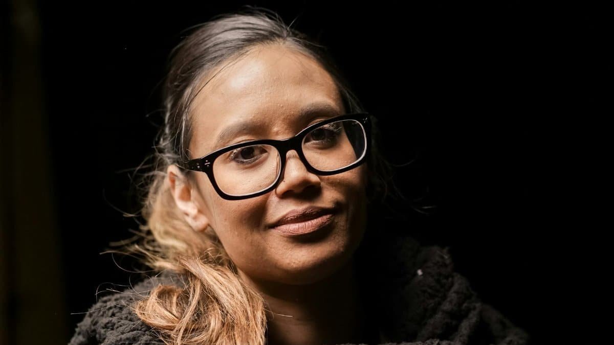 A close-up portrait of a woman with glasses in soft lighting, creating a warm and intimate atmosphere.