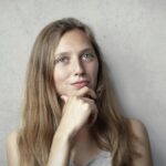 A thoughtful woman contemplates life in a simple portrait with a gray background.