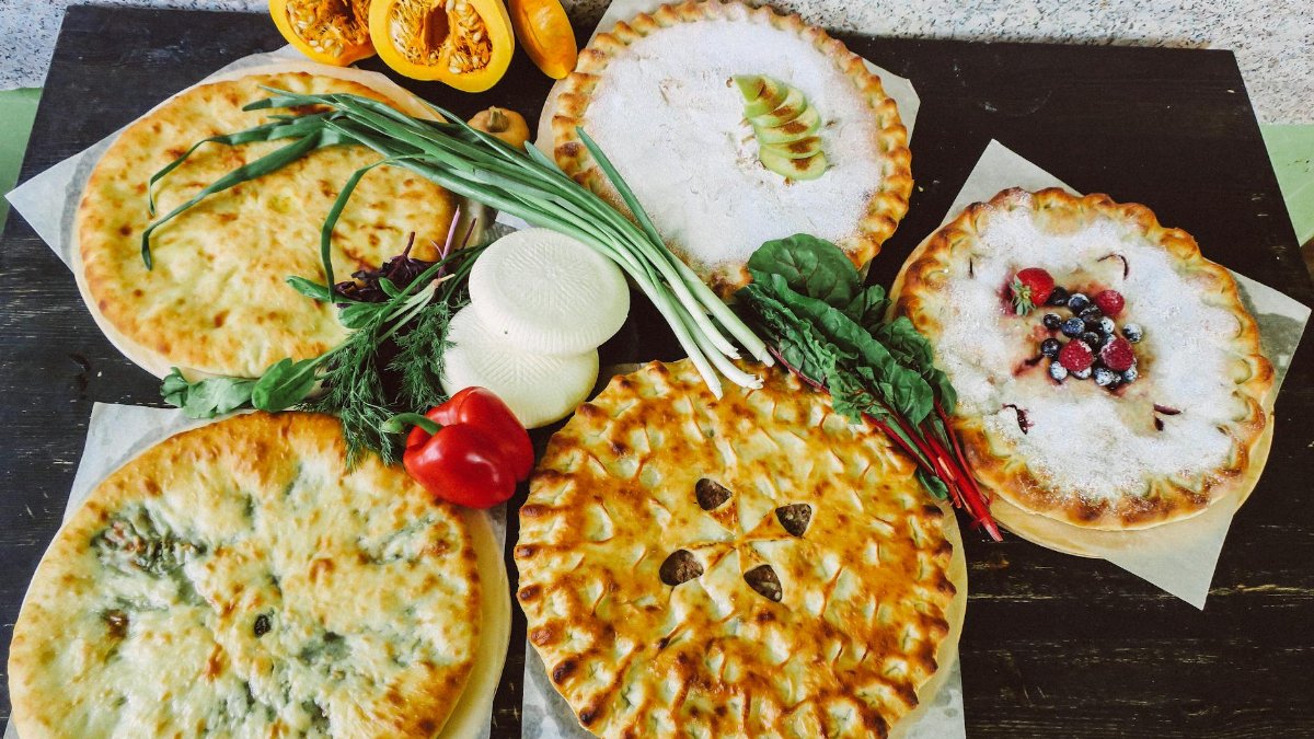 A high-angle view of various pies with fresh vegetables, showcasing a mix of savory and sweet flavors.