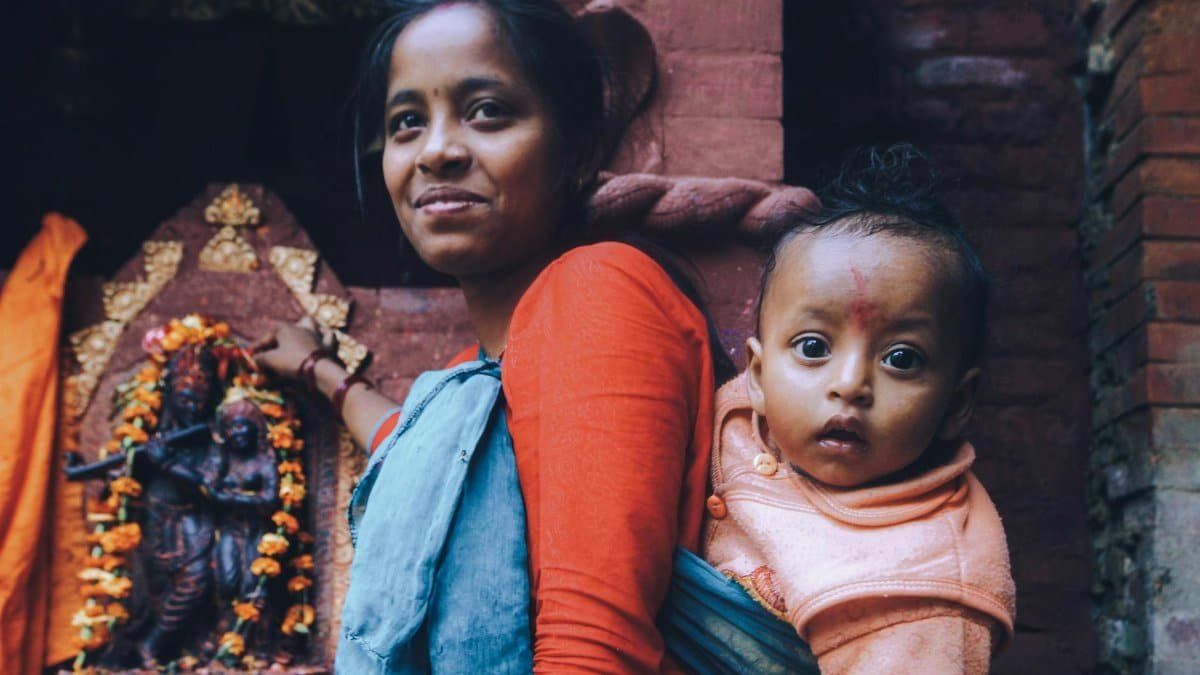 A mother and child pose near a Hindu temple shrine, showcasing cultural and religious aspects.