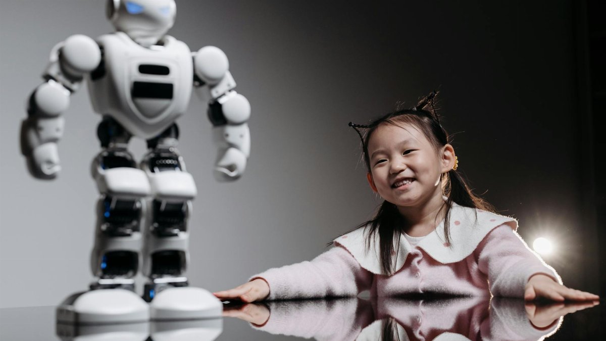 A joyful young girl engages with a high-tech robot toy indoors.