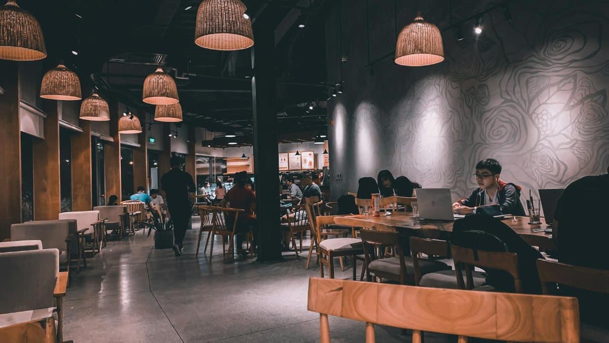 Inviting restaurant interior featuring dim lighting, wooden furniture, and patrons engaged in conversation and work.