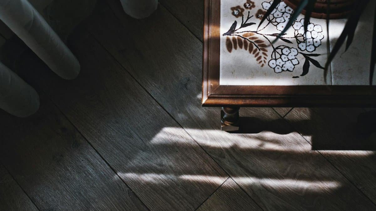 From above of vintage wooden table covered with amazing ornamental tiles placed on parquet floor in cozy room