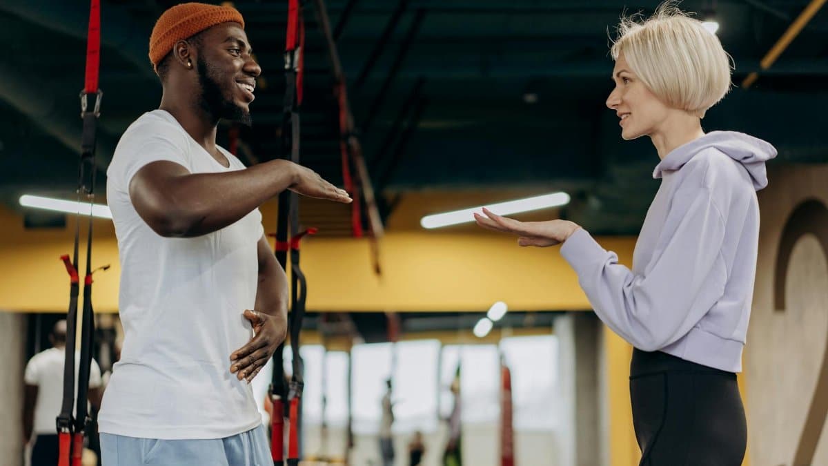 Personal trainer coaching a client during a fitness session in a modern gym environment.