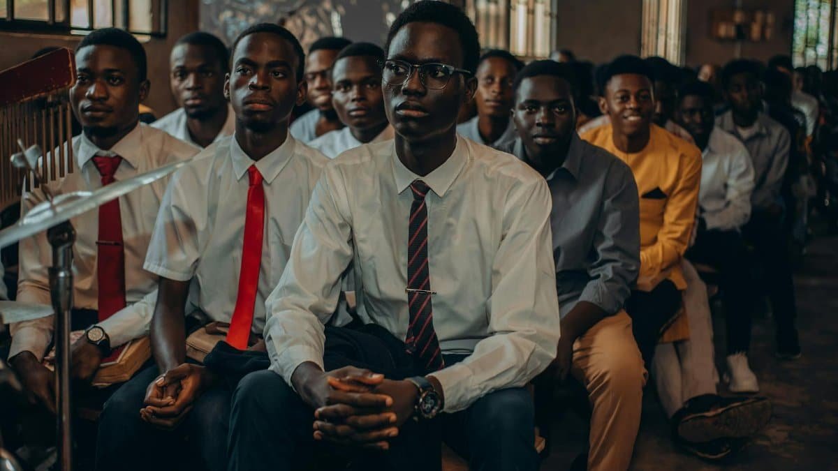 A group of young men dressed formally, seated indoors at an event.