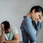 An Asian woman and man feeling misunderstood and frustrated in a relationship indoors.