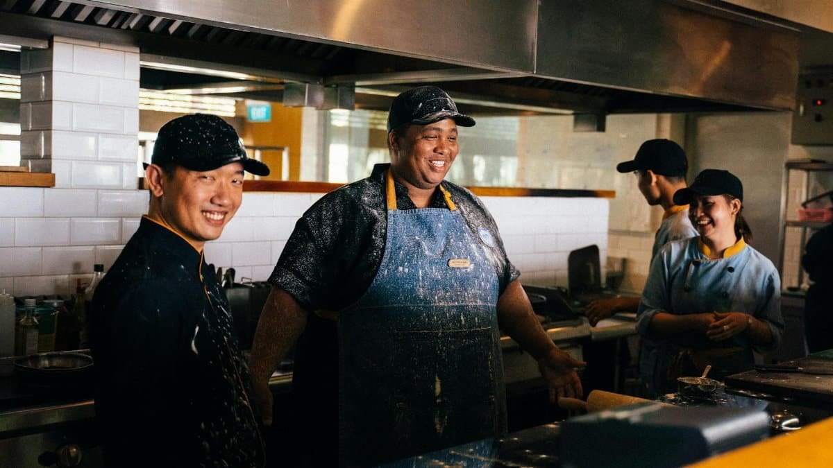 Chefs enjoying their work in a busy restaurant kitchen, highlighting teamwork and culinary passion.