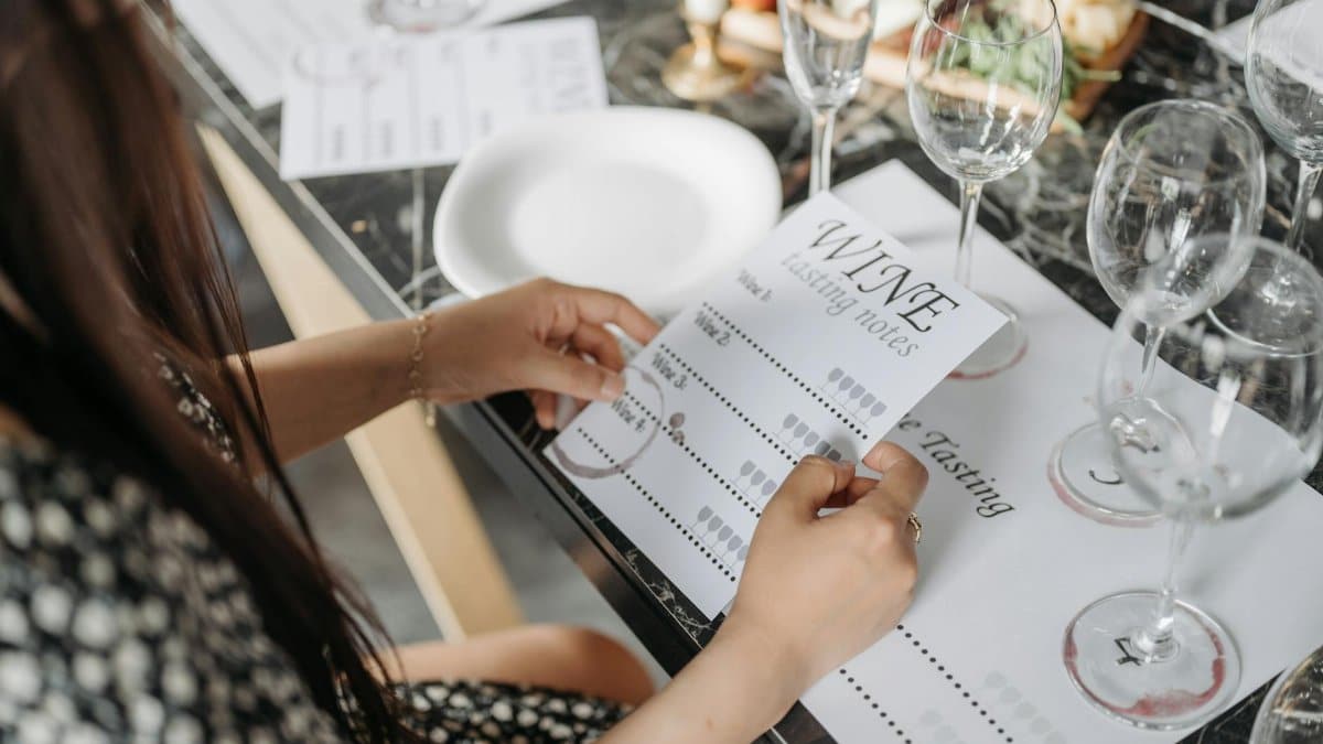 A woman exploring wine tasting notes at an elegantly arranged table in preparation for a wine tasting event.