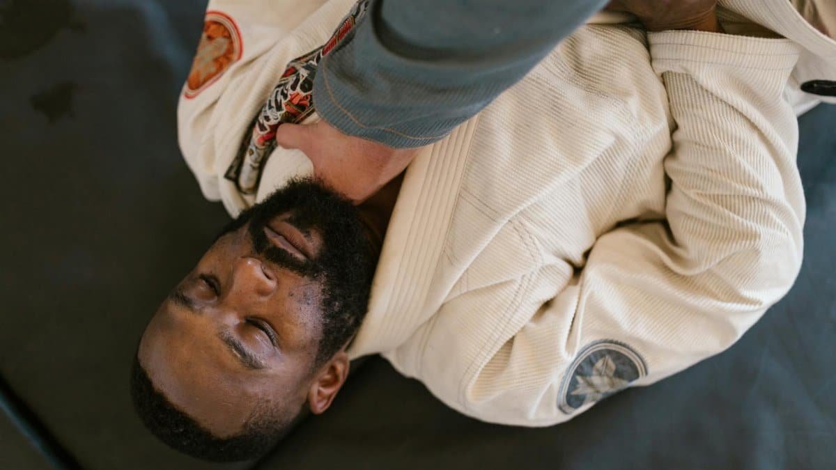 Martial arts practitioners in action during a grappling training session on the mat.