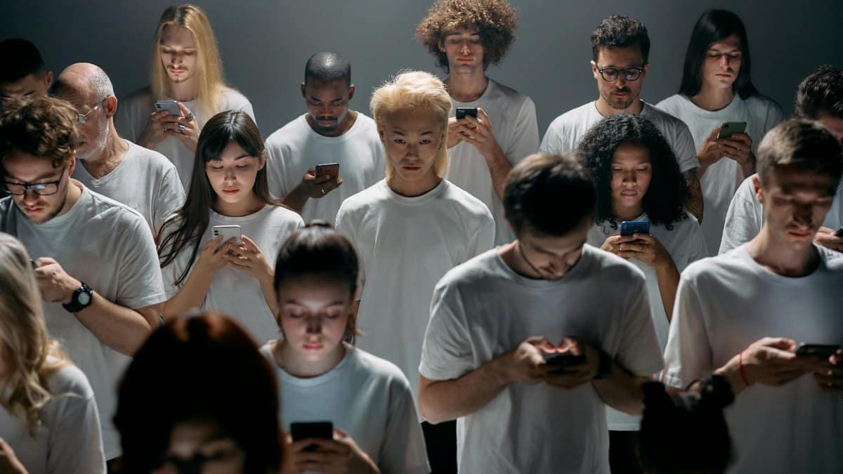 A diverse group of people focused on smartphones indoors, highlighting modern technology's impact.