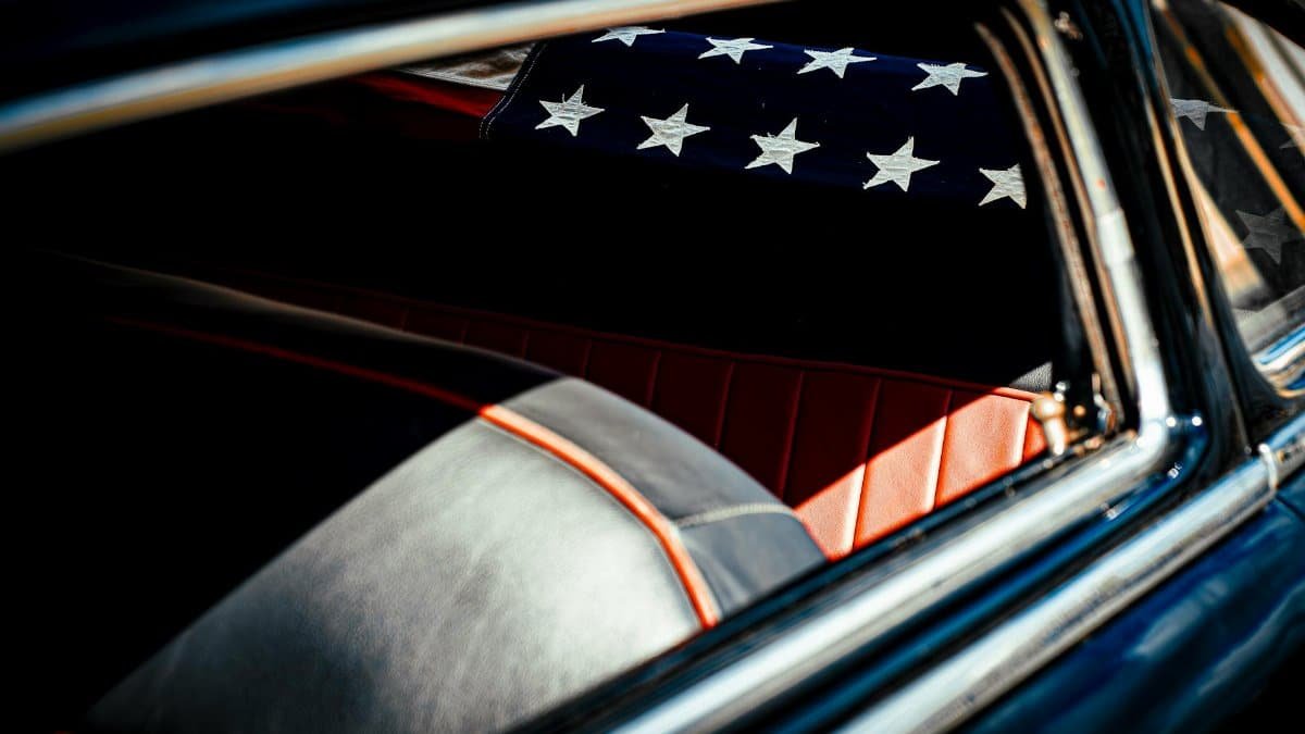 Close-up view of a vintage car interior featuring an American flag, highlighting classic design elements.