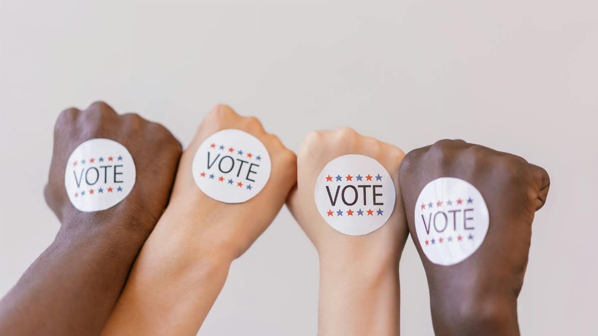 Close-up of diverse hands showing unity with vote stickers emphasizing democracy.