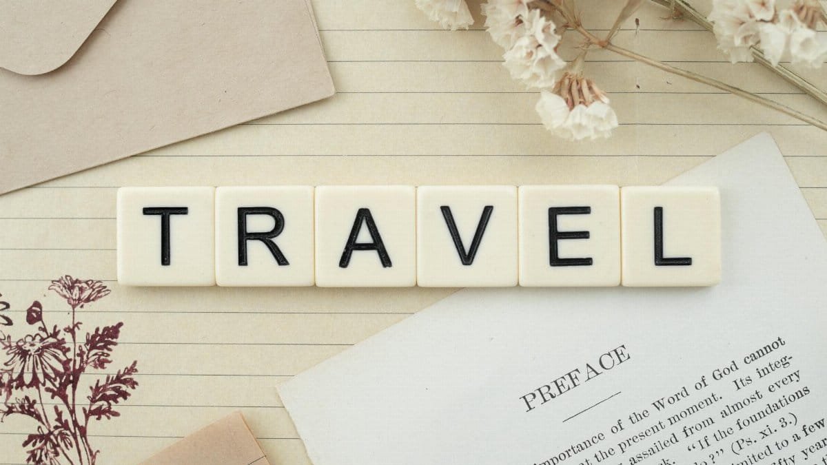 Travel-themed flat lay with Scrabble tiles, dried flowers, and stationery creating a vintage vibe.