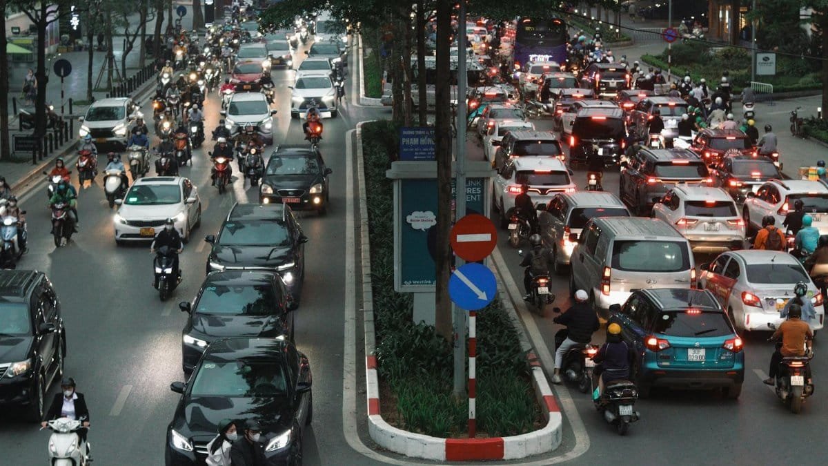 Busy city street packed with cars and motorcycles during evening rush hour.