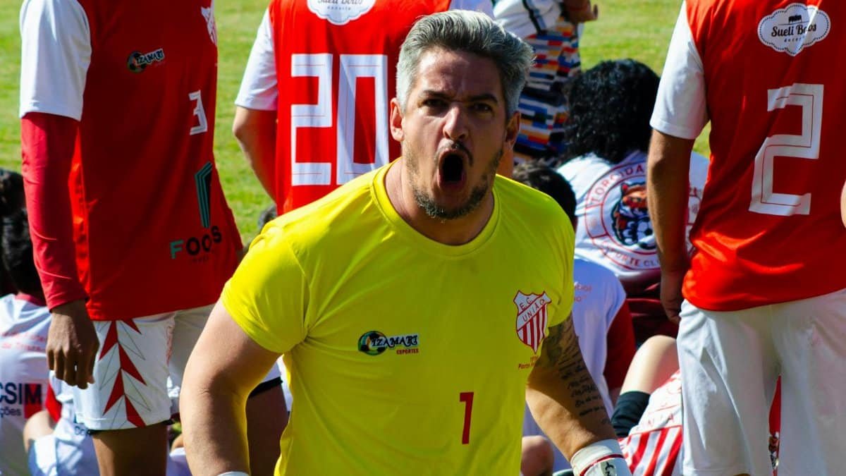 Goalkeeper in action with team during a competitive soccer match outdoors.