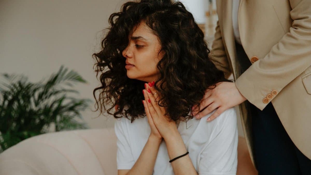 A young woman receives emotional support during a therapy session indoors.