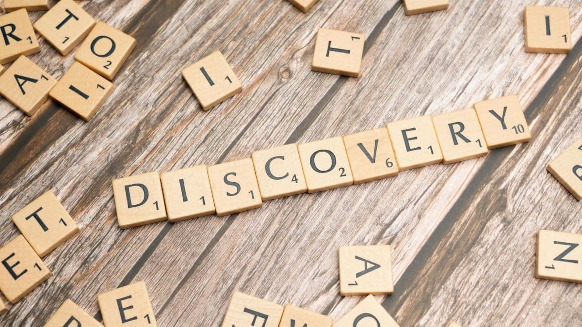 Close-up of wooden letter tiles on a table spelling 'Discovery', representing exploration and creativity.