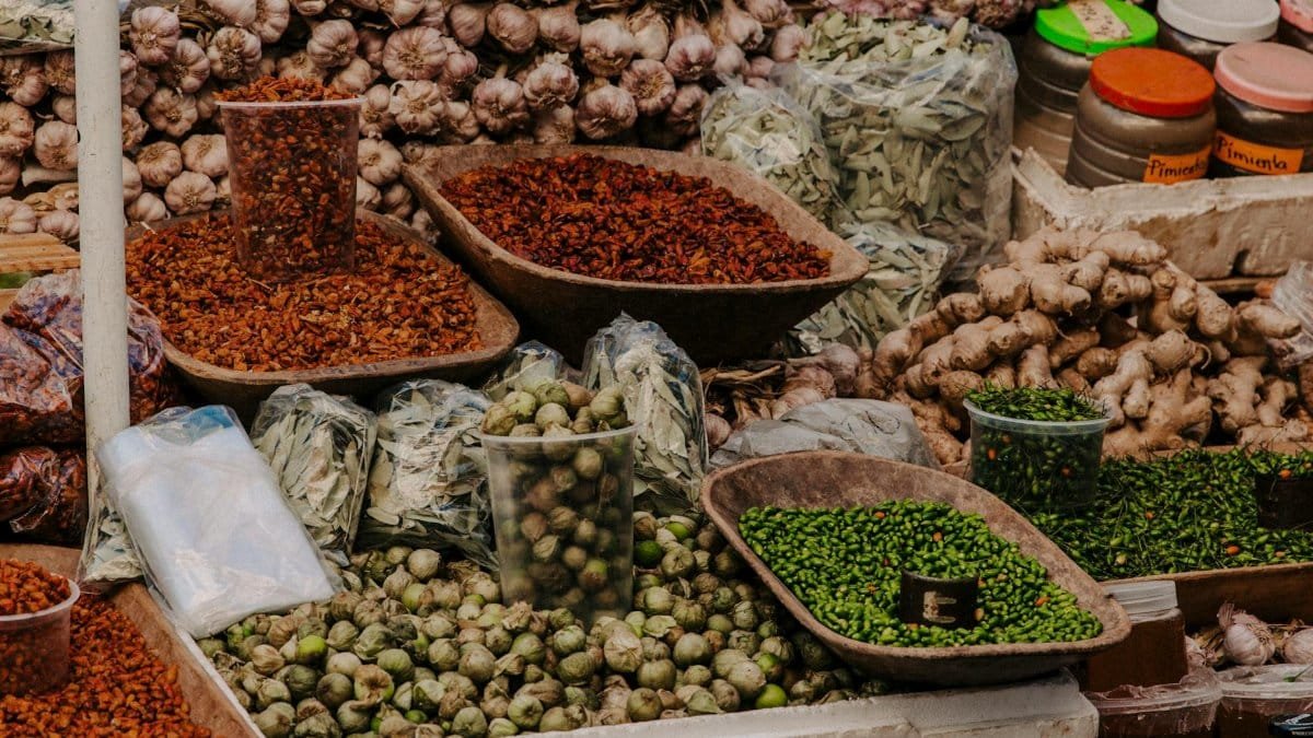 Vibrant display of fresh vegetables, spices, and herbs at a bustling outdoor market.