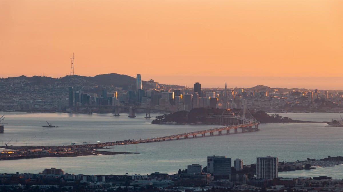 Stunning aerial view of San Francisco cityscape and Bay Bridge during sunset, capturing urban beauty.