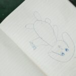 An artistic sketch of a cute cartoon bunny drawn in a lined notebook.