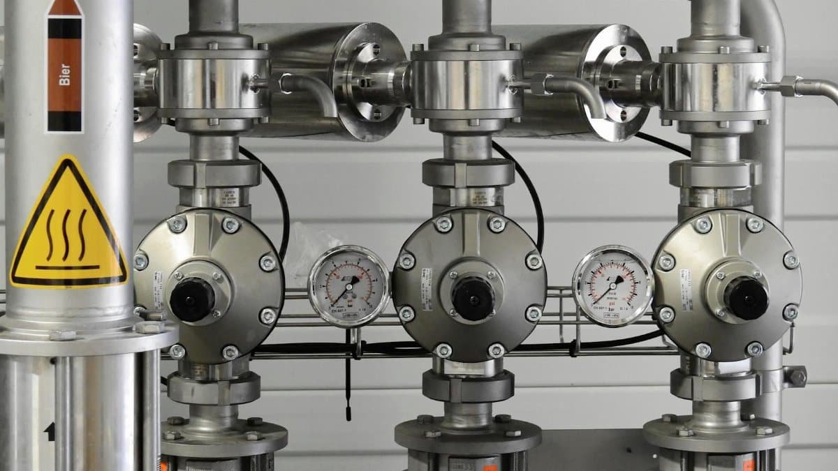 Close-up of stainless steel pipes with pressure gauges in an industrial setting.